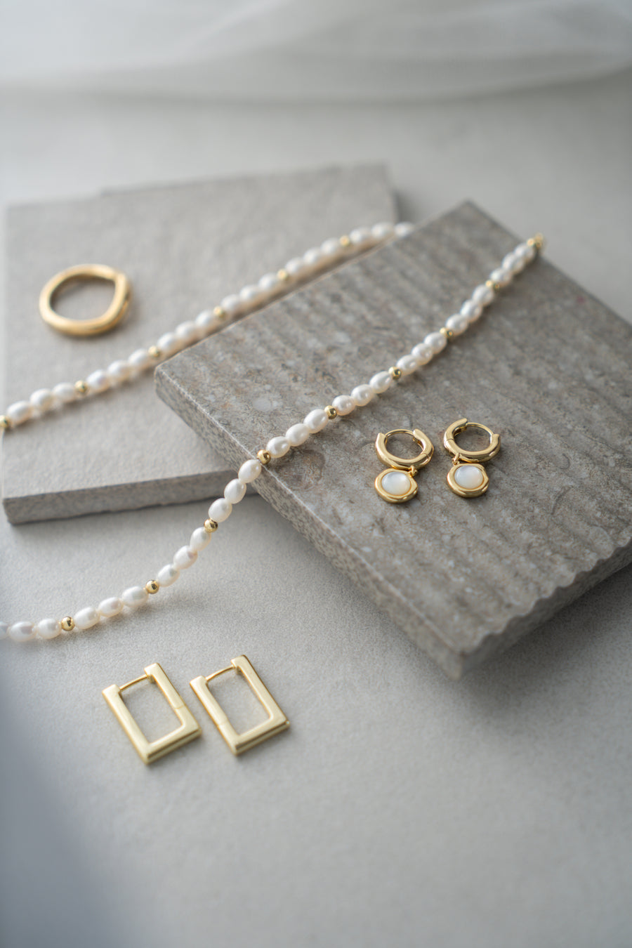 Gold and pearl jewelry set on a textured surface
