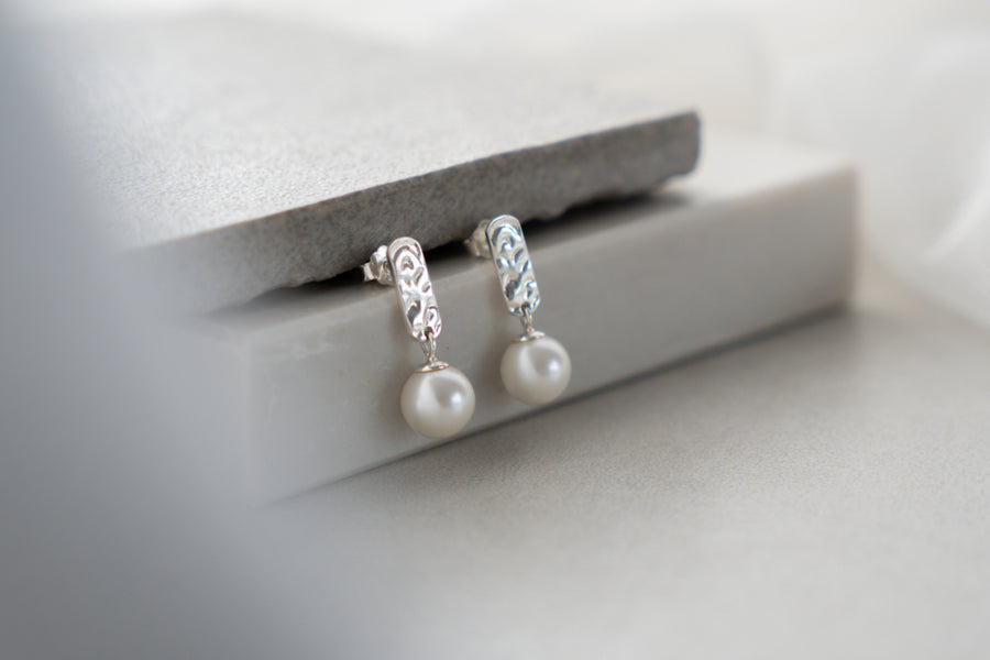 Pearl earrings with silver accents on a white surface