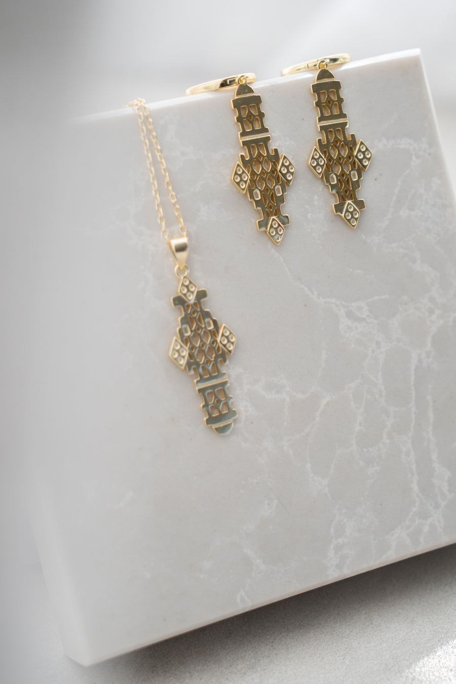 Gold earrings on a white marble surface