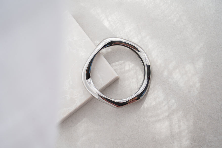 Silver bangle on a textured white surface