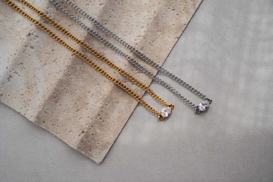 Gold and Silver Necklace with clear stone on grey surface