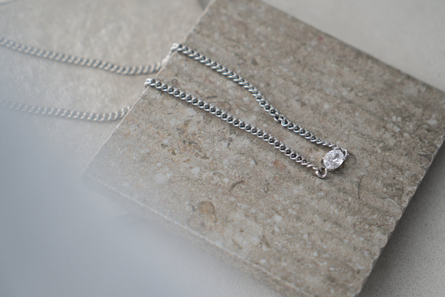 Silver necklace with a pendant on a stone surface